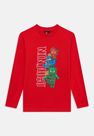 Chemise rouge à manches longues avec trois personnages LEGO Ninjago empilés et texte "NINJAGO" en blanc au centre devant.