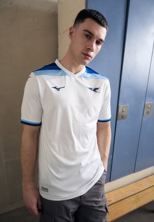 Weißes Sporttrikot mit strukturiertem Muster, das blaue Akzente an den Schultern und Ärmeln aufweist. Kurze Ärmel und ein V-Ausschnitt-Design.
