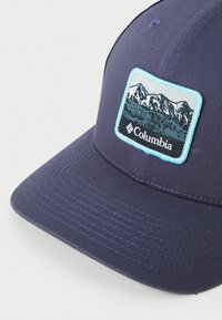 Navy blue cap made of fabric with a flat brim. Features an embroidered mountain scene patch in shades of blue and white.