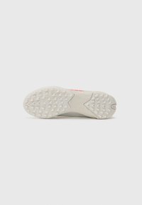 Shoe sole with a textured pattern, predominantly white with light grey accents, featuring a small red logo and a sharp heel design.