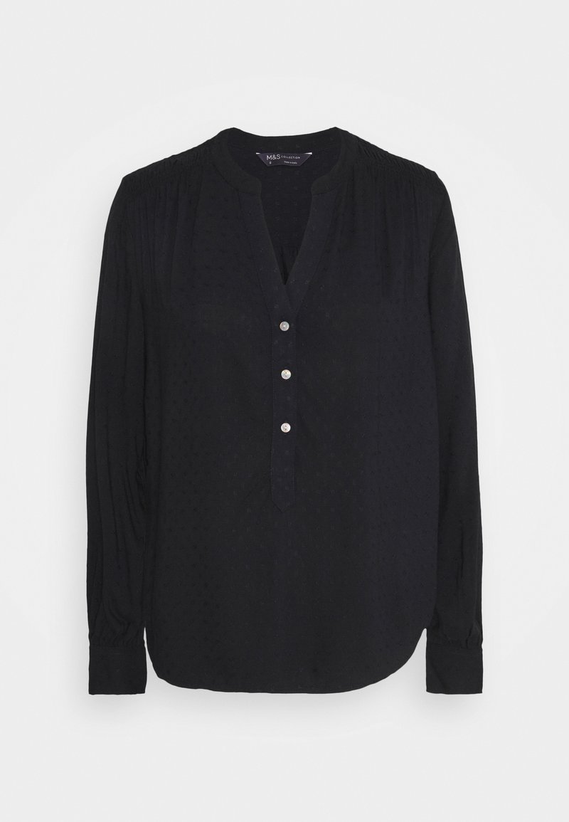 Blusa nera a maniche lunghe con sottili punti testurizzati, tre bottoni frontali, spalle plissettate e orlo arrotondato.
