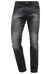 Jean denim noir coupe slim avec texture délavée, design à cinq poches, fermeture à boutons et taille mi-haute sur fond blanc.