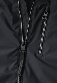 Schwarzer Jackenstoff mit zwei Reißverschlusstaschen. Verfügt über metallische Reißverschlusszüge und eine glatte Textur, geeignet für Outdoor-Bekleidung.