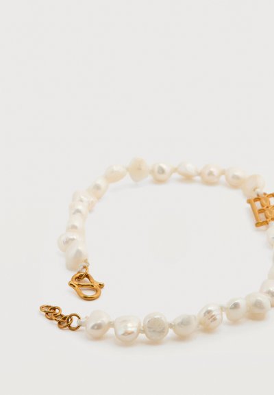 Βραχιόλι με ακανόνιστες λευκές πέρλες και κούμπωμα από χρυσό σε σχήμα αστακού σε λευκό φόντο.