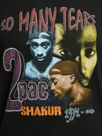 Must hõbedane puuvillane T-särk, millel on graafiline print Tupac Shakur'ist, koos värvilise teksti ja piltidega kollases, sinises ja lillates toonides. Disain sisaldab märgatavaid mustreid.
