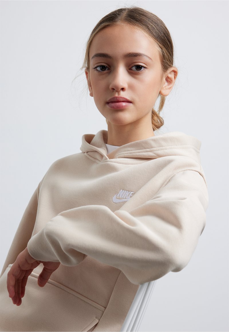 Hanorac Nike bej cu buzunar frontal, material texturat și logo alb pe piept. Dispune de un glugă cu șnur și manșete cu nervuri.
