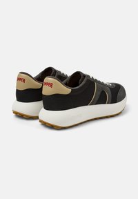 Sneaker in rete nere con dettagli beige, dotate di suola bianca e suola in gomma color nocciola. Logo "Camper" in rosso sul tallone. Design classico con lacci.
