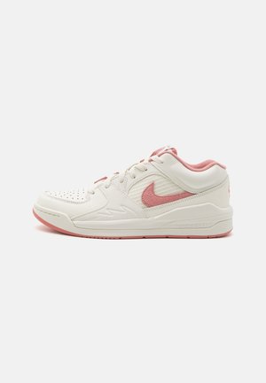 Zapatilla Nike baja en blanco y rosa con puntera perforada, logo lateral texturizado, cuello acolchado y suela de goma.
