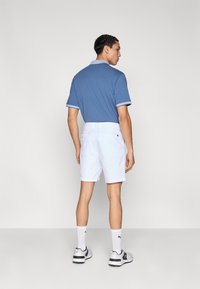 Ανδρικό κοντομάνικο πόλο σε μπλε χρώμα με λευκό γιακά και μανσέτες, συνδυασμένο με λευκό σορτς. Διαθέτει εφαρμοστή σχεδίαση και απαλή υφή υφάσματος.