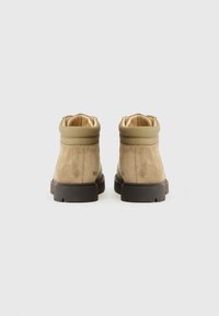 Bottines en daim beige avec une tige khaki lisse, dotées d'un col rembourré, d'une semelle en caoutchouc et de détails minimalistes. Vue arrière montrée.