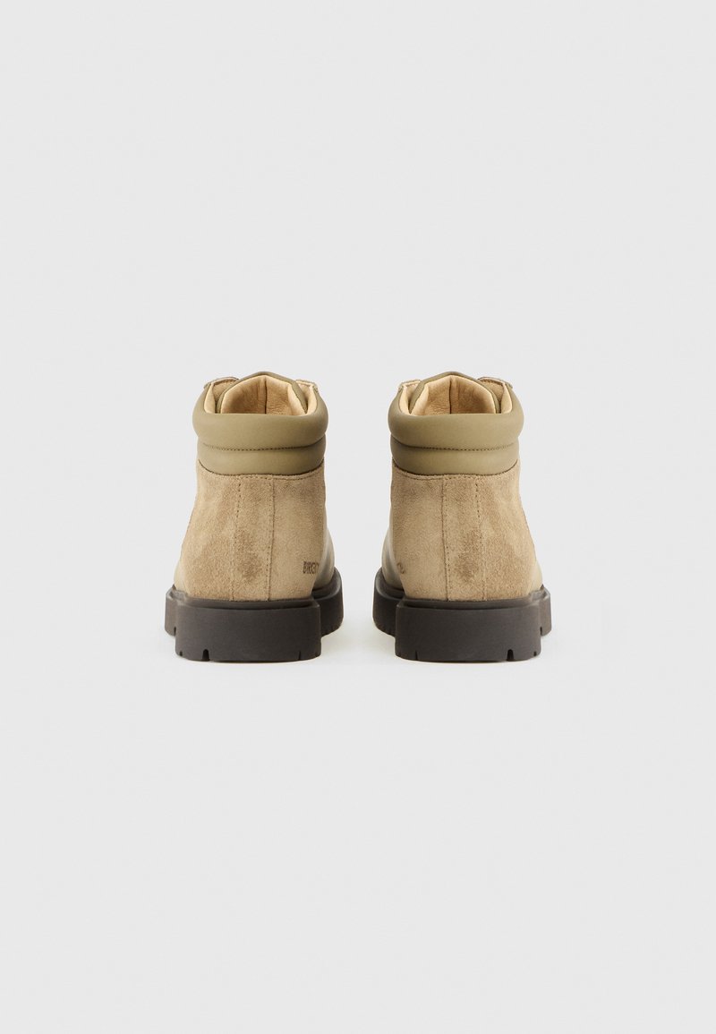 Beige Wildleder-Stiefeletten mit einem glatten khaki Oberteil, featuring einem gepolsterten Kragen, Gummisohle und minimaler Verzierung. Rückansicht dargestellt.