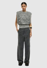 Tyk grå og sort strikket sweater med overdådige skuldre, kombineret med grå bukser med vide ben og sorte sko. Glat tekstur, få detaljer.