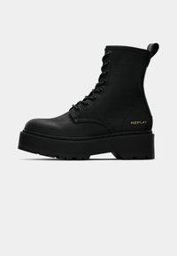 Black lace-up ankle boots made of textured leather. Features a chunky platform sole, prominent lugs, and a pull tab for easy wear. Gold "REPLAY" logo.