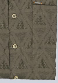 Knitted olive green cardigan with raised diamond and triangle patterns, two cream buttons, and a small chest pocket with a metal tag.