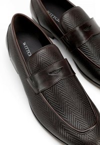 Donkerbruine leren loafers met een visgraatpatroon, voorzien van een brede band en subtiele hardwaredetails, met een gladde textuur en een gepolijste afwerking.