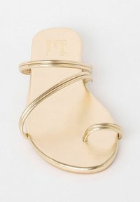 Gouden sandaal met een platte zool en meerdere dunne gebogen bandjes. Gladde, metallic afwerking met een ronde neus en een minimalistisch ontwerp.
