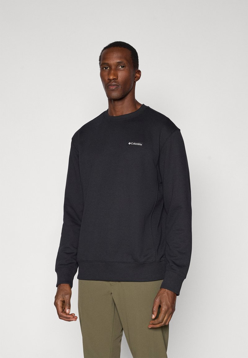 Sweatshirt noir en coton avec col ras du cou, poignets et ourlet côtelés, et un petit logo Columbia blanc sur la poitrine.
