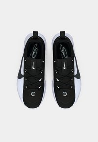 Μαύρα και άσπρα αθλητικά παπούτσια με υφή στην επάνω πλευρά, λεία μύτη, σχέδιο με κορδόνια και επιβλητικό λογότυπο στην γλώσσα και στο πλάι.