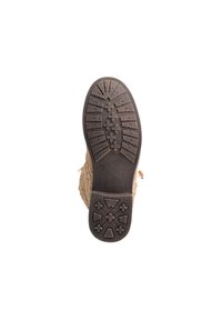 Suela de bota beige con goma texturizada que presenta un patrón de diamantes y flechas para mayor tracción, bordeada con un material superior ligero y suave.