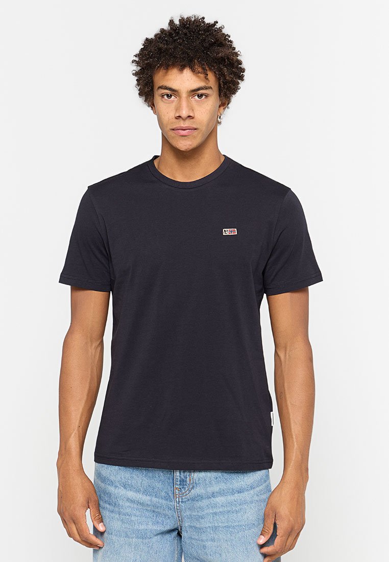 T-shirt blu navy a maniche corte, colletto rotondo, realizzato in cotone, presenta un piccolo logo sul petto, abbinato a jeans azzurri.