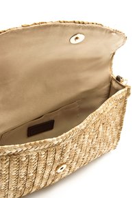 Sac à main en paille tissée avec un intérieur en tissu beige. Dispose d'une fermeture à pression magnétique et d'une petite poche intérieure.
