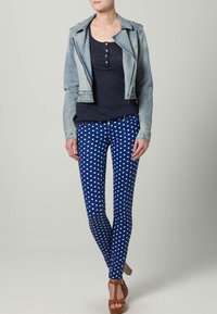 Jeansjacke, blaues Tanktop, navy und weiße gepunktete Leggings, braune High Heels Sandalen, eng anliegendes Design, lässiger Stil.