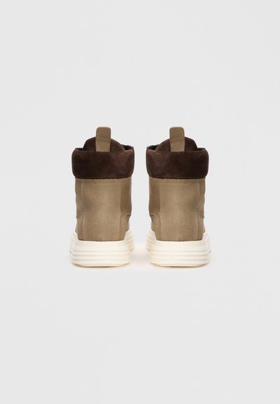 Botas de tobillo de ante marrón con suela de goma beige, que cuentan con un suave puño doblado y una lengüeta en el talón para facilitar su uso.