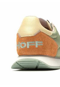 Zapatilla de cuero verde y gamuza beige con acentos naranjas. Presenta "HOFF" en bordado azul claro en el talón. Suela de goma gruesa.