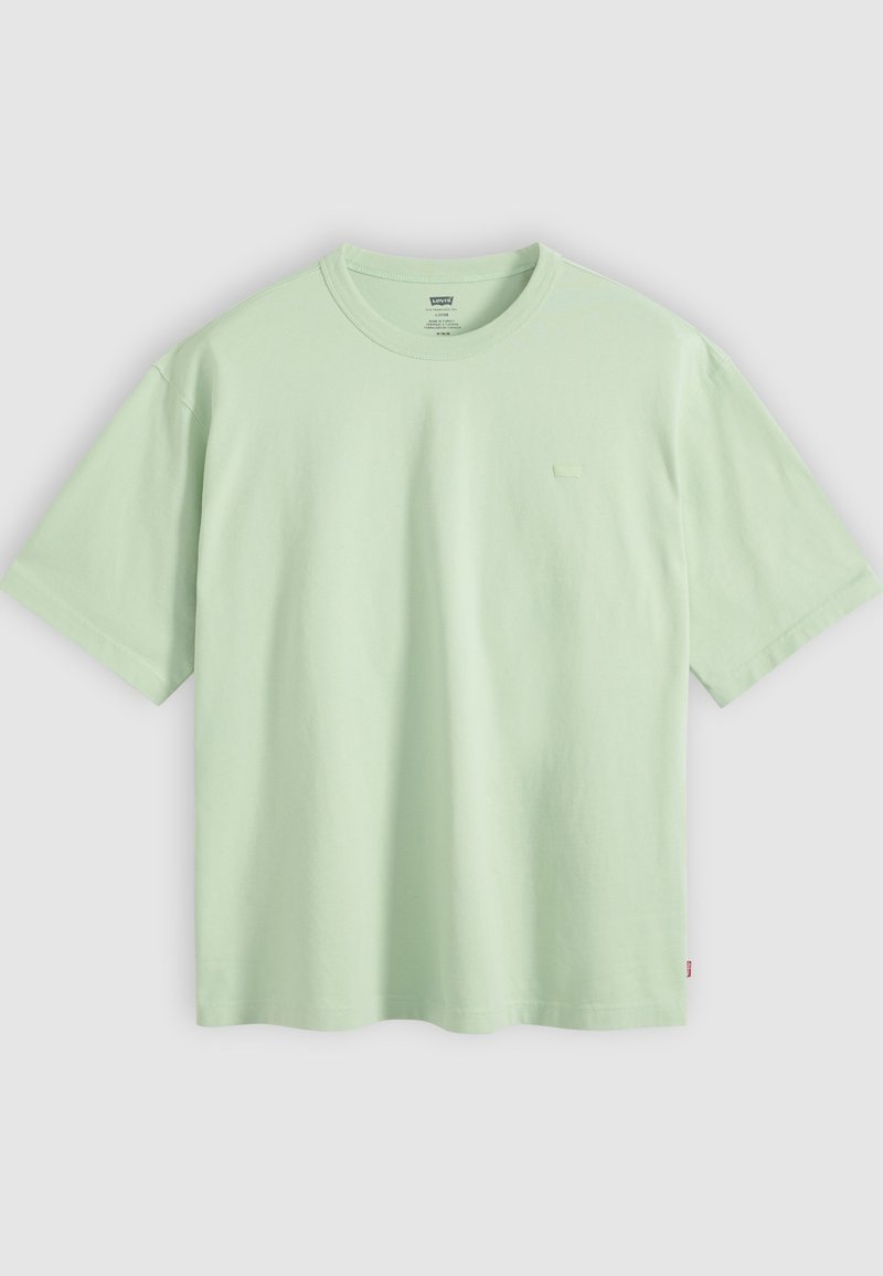 T-shirt en coton vert clair uni à manches courtes, col rond, avec une petite étiquette de marque sur le côté gauche près de l'ourlet.