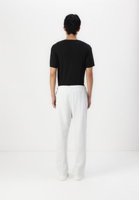 Sort t-shirt med korte ærmer parret med lysegrå sweatpants. Bukserne har en elastisk talje og smalnende ben.