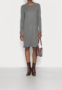 Robe en tricot grise à manches longues et col rond. Assortie à des bottines cheville en cuir crocodile brun et un sac à main coordonné.
