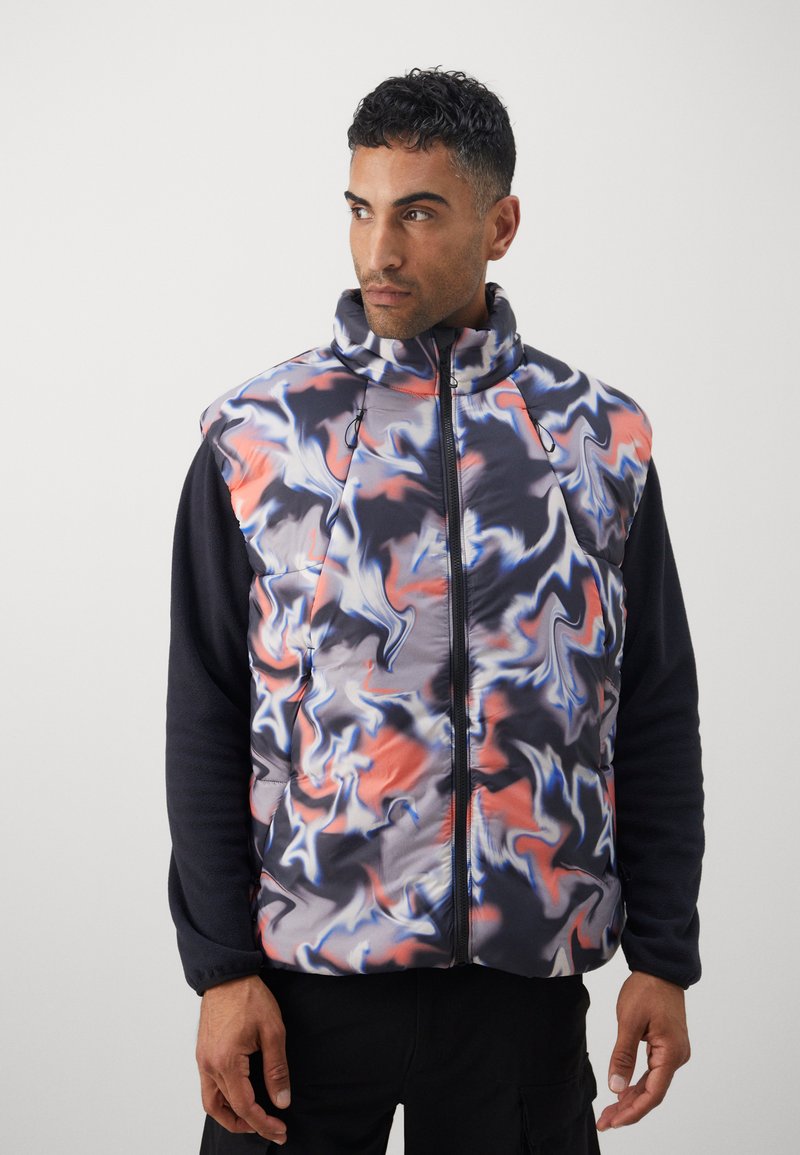 Pufjakas ar daudzkrāsainu viļņotu rakstu melnā, oranžā un zilā tonī; ar augstu apkakli un priekšējo rāvējslēdzēju, apvienota ar melnu gariem piedurknēm.