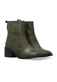 Pár olivově zelených kožených kotníkových bot s nízkými blokovými podpatky a poutky na zadní straně na bílém pozadí.