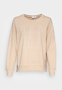 Felpa beige con maniche lunghe, polsini e orlo a costine. Presenta un grande testo bianco "GAP" sulla parte anteriore. Tessuto morbido al tatto.