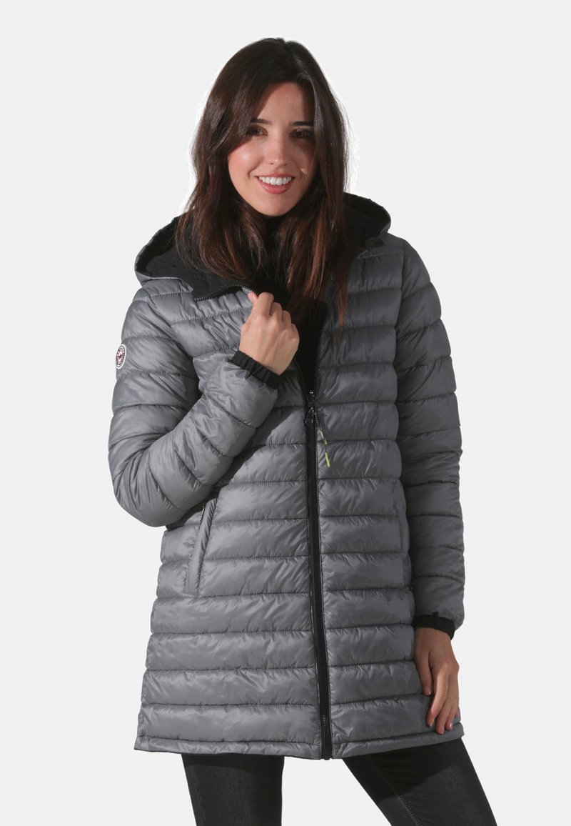 Veste matelassée grise avec un design matelassé, capuche noire ajustable, fermeture éclair à l'avant et poches latérales, avec des poignets élastiques et un détail de logo.