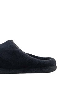 Svart fällfodertoffel med mjuk textur, rund tå och platt sula. Har en sömlös design och minimalistisk profil.