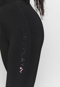 Zwarte legging met een hoge tailleband, een gladde textuur en een bedrukt logo "ONLY PLAY" langs de zijkant met kleurrijke stippen.