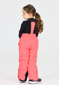 Rosa isolierte Schneehosen mit verstellbaren Trägern, elastischem Bund und seitlichen Reißverschlüssen, kombiniert mit einem schwarzen Langarmshirt.