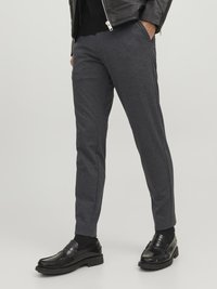 Grå avsmalnande byxor i mjukt tyg, med sidofickor och en jämn yta, kombinerat med svarta läder loafers.