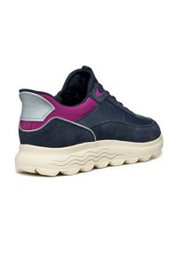 Marineblauer Sneaker aus Wildleder und Synthetikmaterial, mit lila Akzenten, abgerundeter weißer Sohle mit Wellenmuster, Schnürdesign und gepolstertem Schaft.