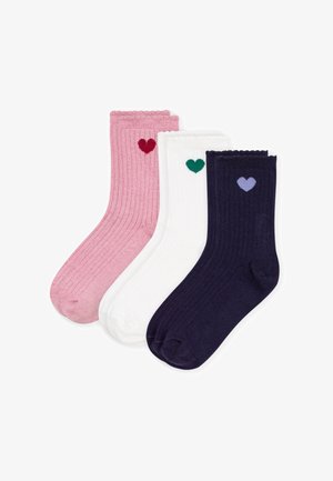 Trois paires de chaussettes côtelées en rose, blanc et bleu marine, chacune avec un petit cœur près du haut en rouge, vert et violet respectivement.