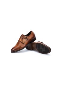 Zapatos de cuero marrón con dobles hebillas, punta redondeada y un acabado suave. La suela presenta un patrón texturizado para ofrecer agarre.