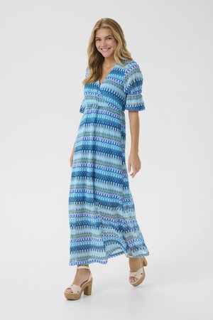 Maxi dress featuring a blue, green, and purple wavy zigzag pattern, short flutter sleeves, and a deep V-neck design. Worn with beige platform sandals.