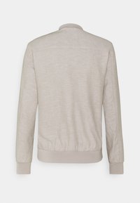 Jasnobeżowa kurtka bomberka o gładkiej strukturze, z prążkowanymi mankietami i ściągaczem na dole oraz prostym okrągłym dekoltem; bez widocznych zapięć i wzorów.