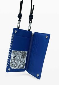 Blå plånbok med dragkedjestängning, som har en strukturerad ormskinnstrykt kortficka, slät insida och knutna svarta remmar med silverdetaljer.