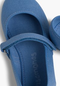 Zapatos Mary Jane de lona azul con puntera redondeada, correa ajustable y detalles de costura en contraste. Interior de tela suave.