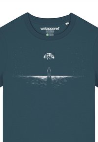 Donkerblauwe katoenen T-shirt met een witte afbeelding van een astronaut die op een reflecterend oppervlak staat, met een grote hemelse lichaam erboven.