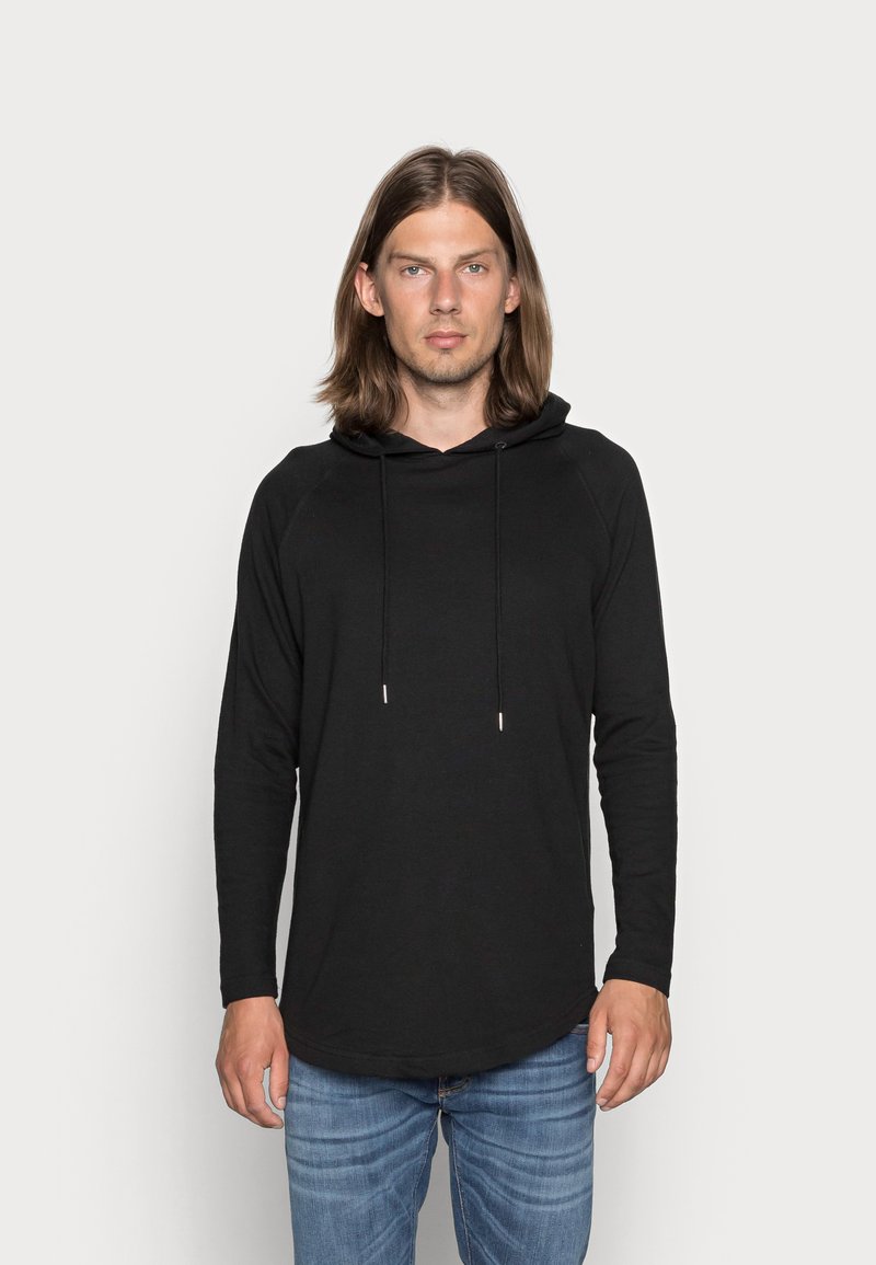 Sort langærmet hættetrøje med en afslappet pasform, der har snøre i hætten og en glat tekstur. Bæres med blå jeans.