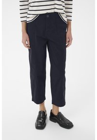 Pantalons cropped bleu marine en coton, avec une fermeture à boutons à l'avant, des poches latérales et une coupe décontractée. Associés à des mocassins noirs.