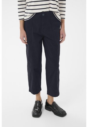 Marineblaue, cropped Hose aus Baumwolle mit einem Knopfverschluss vorne, seitlichen Taschen und einem lockeren Schnitt. Kombiniert mit schwarzen Mokassins.